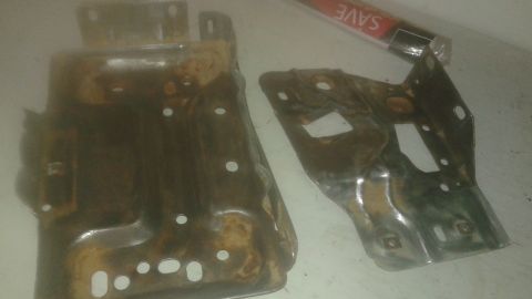 1996 Ford Bronco - Two rusty metal automotive parts are shown on a light-colored surface. A partially visible tube with the word "SAVE" printed on it is in th…