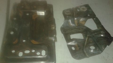 1996 Ford Bronco - Two metal automotive parts, possibly from a 1996 Ford Bronco, are laid out on a light-colored surface. The parts appear to be made of steel…