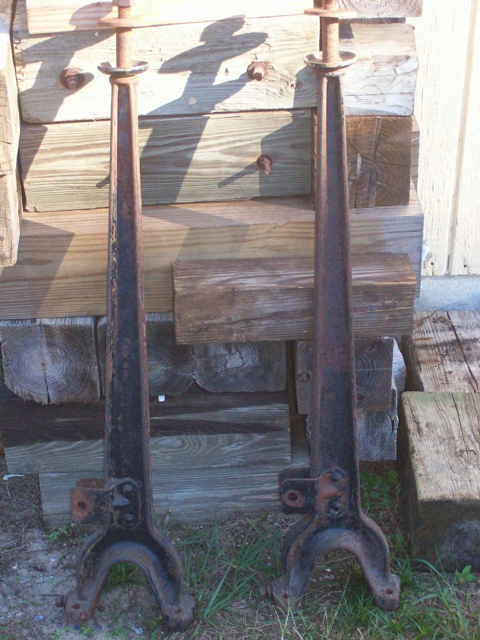 Two rusty cast iron parts, possibly vehicle supports or legs, standing upright.