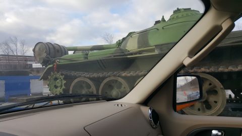 1995 Ford Bronco - A military tank is transported on a trailer, viewed from the perspective of a passenger in another vehicle.