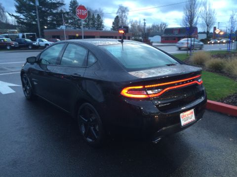 2015 Dodge Dart - The rear of a black Dodge Dart sedan is visible, with its distinctive LED taillights illuminated.