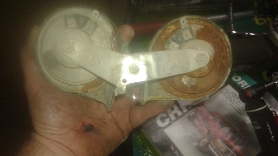Dual horn assembly held in hand, showing rust