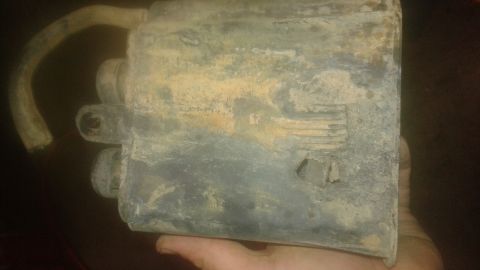 1996 Ford Bronco - This heavily corroded automotive part has a curved hose attached to its side.