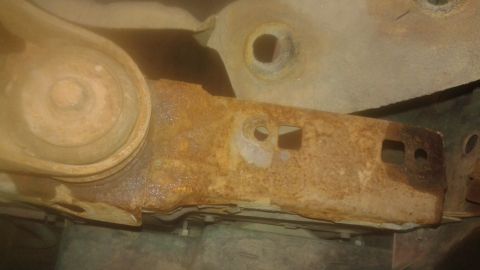 1996 Ford Bronco - The underside of a vehicle shows significant rust on its frame components.