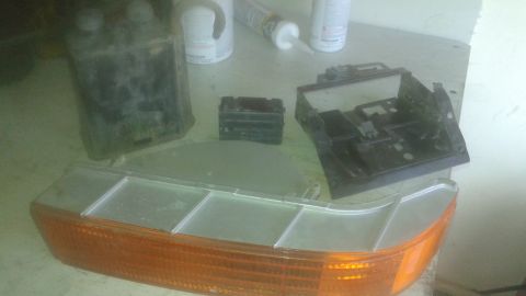 1996 Ford Bronco - Various car parts, including an orange turn signal assembly and black plastic components, are laid out on a surface.