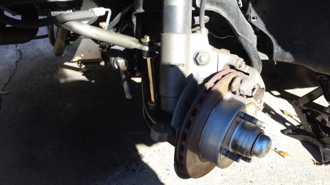 1980 Ford Mustang - Close-up view of a vehicle's front suspension and brake system, showing the rotor, caliper, and steering linkage.