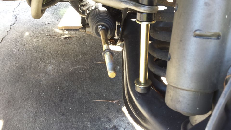 Close-up of a car's front suspension components, including a sway bar link and part of the steering rack