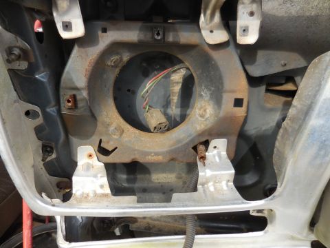 1979 Ford Bronco - Close-up of a vehicle's headlight mounting bracket, showing rust and wiring.