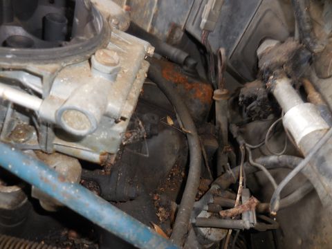 1979 Ford Bronco - A close-up view of a carburetor and various engine parts, showing signs of wear and tear.