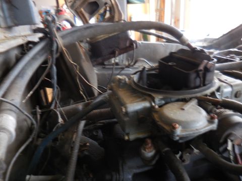 1979 Ford Bronco - A close-up view of a vehicle's engine bay, focusing on the carburetor and brake fluid reservoir.