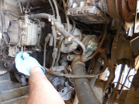 1979 Ford Bronco - Engine bay detail with carburetor and various hoses, a hand is visible working on the carburetor.