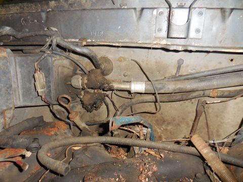 1979 Ford Bronco - Close-up view of the engine bay, showing various hoses and wiring harnesses, some of which appear worn and dirty.