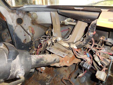 1979 Ford Bronco - The interior of a classic Ford Bronco shows a complex and somewhat disorganized wiring harness behind the dashboard, with various connector…