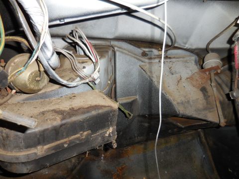 1979 Ford Bronco - This image shows the dusty interior of a vehicle, focusing on the heater box and wiring harness located under the dashboard. Various wires…