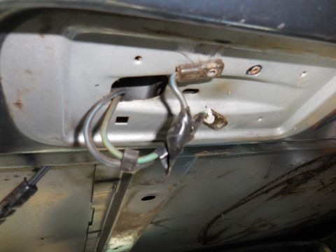 1979 Ford Bronco - Close-up view of wiring harness and connectors attached to the underside of a vehicle's body panel. The wires appear to be blue, yellow, an…