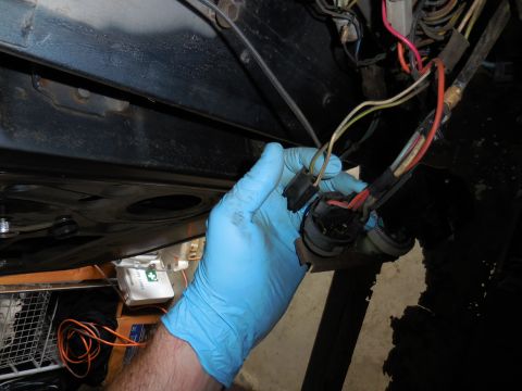1979 Ford Bronco - A gloved hand holds a bundle of electrical wiring and connectors, likely from a vehicle's ignition system, against a dark background.