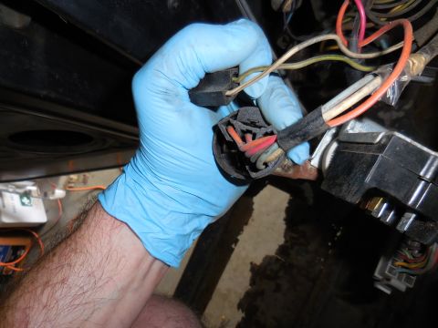 1979 Ford Bronco - A gloved hand is shown disconnecting a wiring harness from a vehicle's ignition switch assembly. The harness contains multiple wires of var…