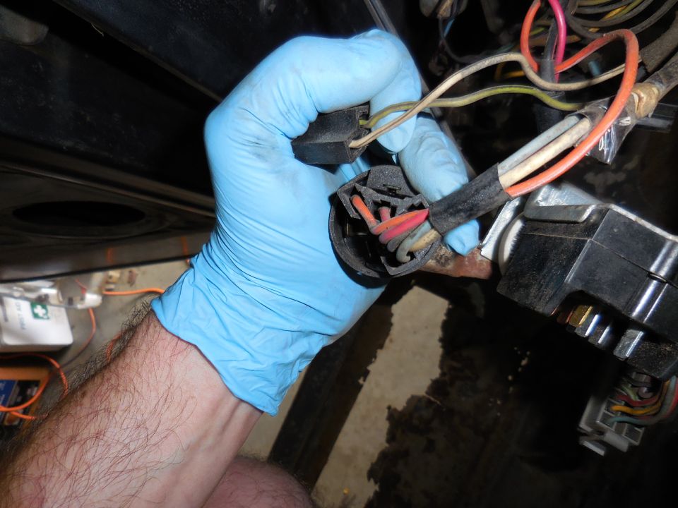 Gloved hand disconnecting wiring harness from ignition switch assembly.