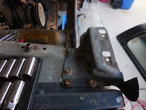 1979 Ford Bronco - A close-up view of a vehicle's engine bay and fender area, showing various tools and rusted metal components. A black car door or panel is…
