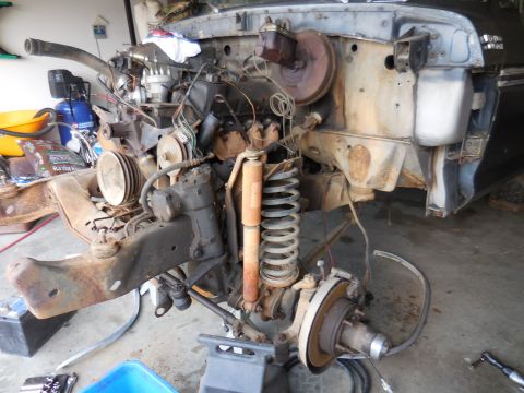 1979 Ford Bronco - The front end of a disassembled vehicle, likely a 1979 Ford Bronco, is shown in a garage setting. The engine, suspension components, and st…