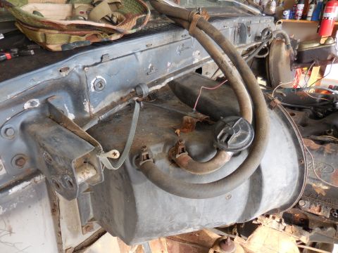 1979 Ford Bronco - The engine bay of a classic Ford Bronco shows a large, dark-colored heater core assembly with two rubber hoses attached. Various metal brac…