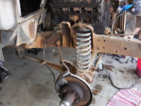 1979 Ford Bronco - The front suspension and engine of a heavily rusted vehicle are visible, undergoing repair or disassembly.