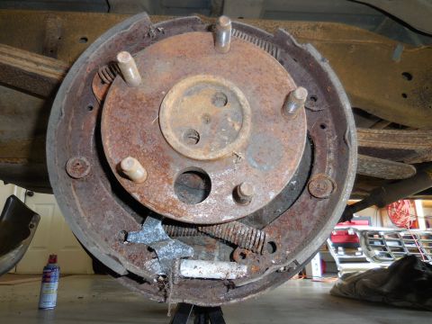 1979 Ford Bronco - Close-up of a heavily rusted brake drum assembly, showing internal components like shoes and springs.