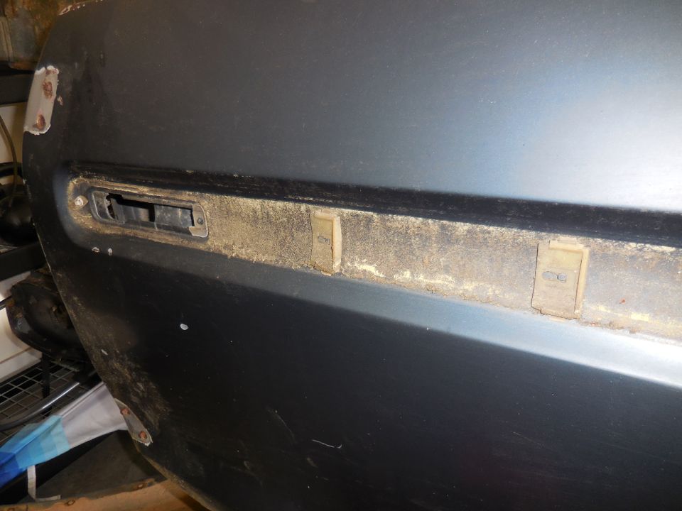 Dark blue door panel with trim clip holes and weathered trim strip