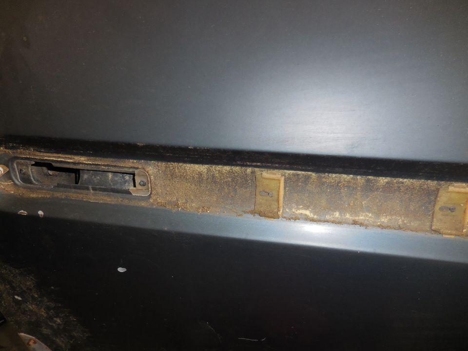Close-up of a dusty interior door latch mechanism with visible mounting points