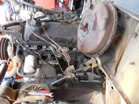 1979 Ford Bronco - A close-up view of a heavily used and dirty engine bay, likely from a classic Ford Bronco. The image focuses on the engine block, brake boo…