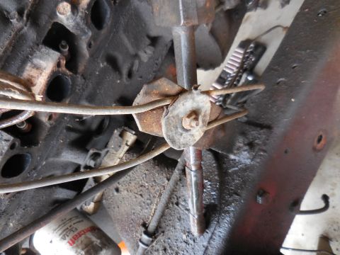 1979 Ford Bronco - A close-up view of the engine bay of a classic Ford Bronco, showing greasy engine components, fuel lines, and a rusted bracket holding them…