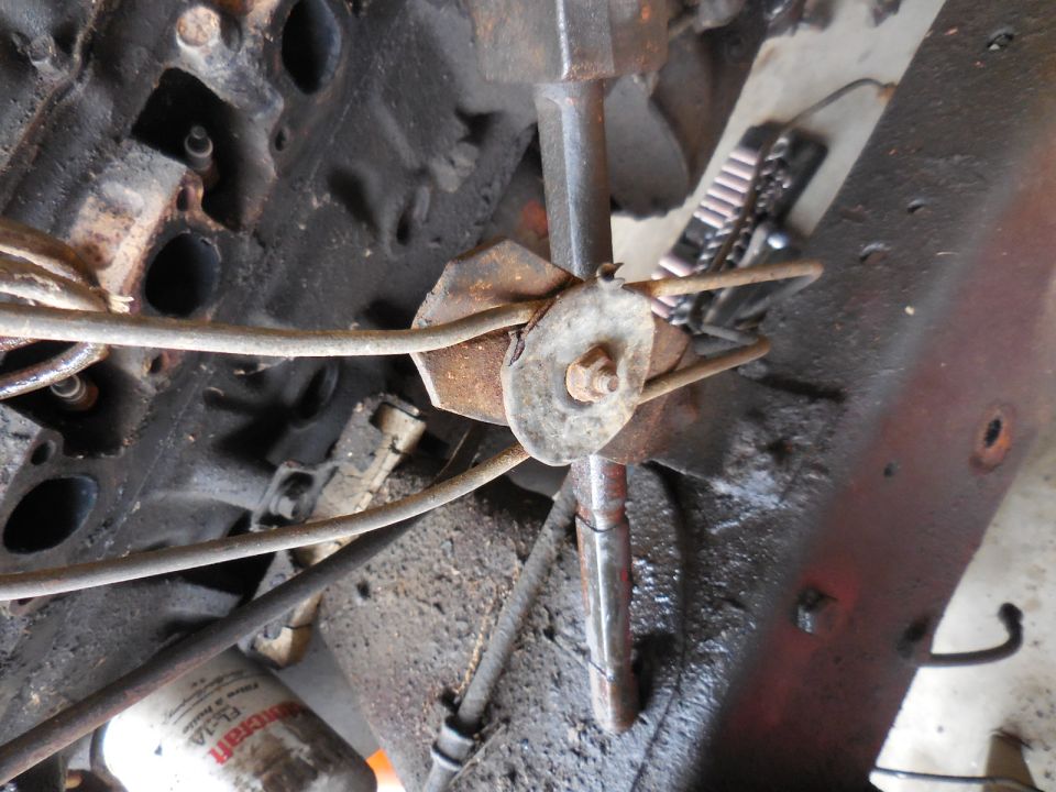 Close-up of greasy engine bay with fuel lines and rusted bracket.