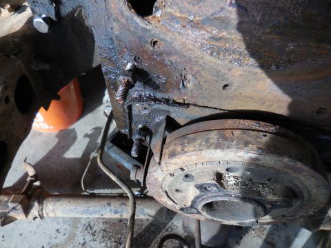 1979 Ford Bronco - A close-up view shows a heavily rusted and greasy engine component, possibly a crankshaft pulley, attached to a vehicle frame with visible…