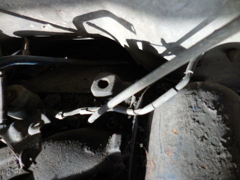 1979 Ford Bronco - This image shows a close-up view of the underside of a vehicle, focusing on brake lines and suspension components. The scene is dusty and a…
