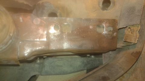 1996 Ford Bronco - This is a close-up, low-angle shot of a heavily rusted metal bracket attached to the underside of a vehicle. The bracket has several holes…