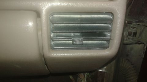 1996 Ford Bronco - A close-up view of a dusty air vent on the interior dashboard of a vehicle. The vent is rectangular with horizontal slats and a small adjus…
