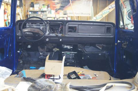 1979 Ford Bronco - The interior of a blue Ford Bronco is shown during a restoration, with the dashboard, steering wheel, and floor exposed. Tools and a cardbo…