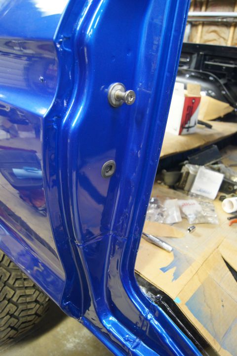 1979 Ford Bronco - A close-up view of the driver's side door jamb of a vehicle with a bright blue metallic paint finish. Two silver fasteners are visible on t…