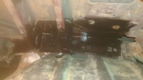 1996 Ford Bronco - The underside of a vehicle shows a black painted metal component, likely part of the frame or suspension, with some rust visible on surroun…