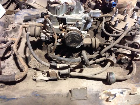 1979 Ford Bronco - A close-up, dusty view of a V8 engine, likely from a classic Ford Bronco, showing the carburetor, spark plug wires, and various vacuum line…
