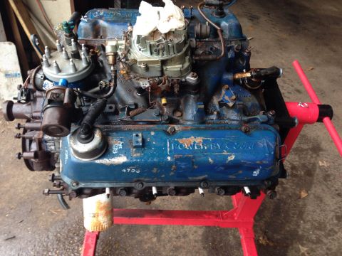1979 Ford Bronco - A blue Ford V8 engine is mounted on a red engine stand. The engine has a carburetor, distributor cap, and "POWER BY Ford" text visible on t…