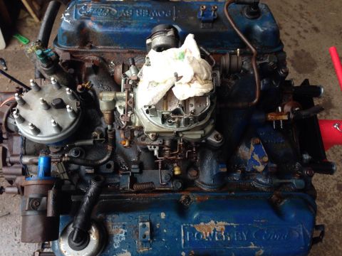 1979 Ford Bronco - A blue Ford V8 engine is shown from a top-down perspective, featuring a carburetor, distributor cap, and various hoses and wires. The engin…