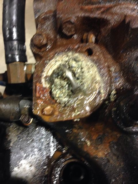 1979 Ford Bronco - A close-up view shows a heavily corroded and grimy engine component, likely part of a cooling system, with a buildup of green and white res…