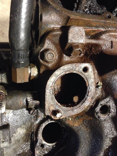 1979 Ford Bronco - A detailed view of a metal engine part with bolt holes, showing its mechanical construction.