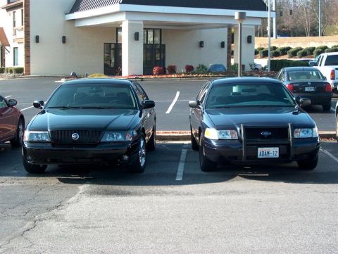 2001 Ford Crown Victoria - Two sedans are parked in front of a building, one is a Mercury Grand Marquis and the other is a Ford Crown Victoria.