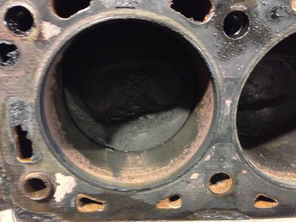 Engine block with two cylinders, showing rust and damage