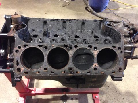 1979 Ford Bronco - Engine block on a red stand, showing cylinder bores and external components.