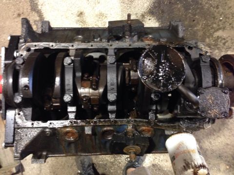 1979 Ford Bronco - An overhead view of a heavily soiled engine block with the oil pan removed, revealing the crankshaft, connecting rods, and oil pickup scree…