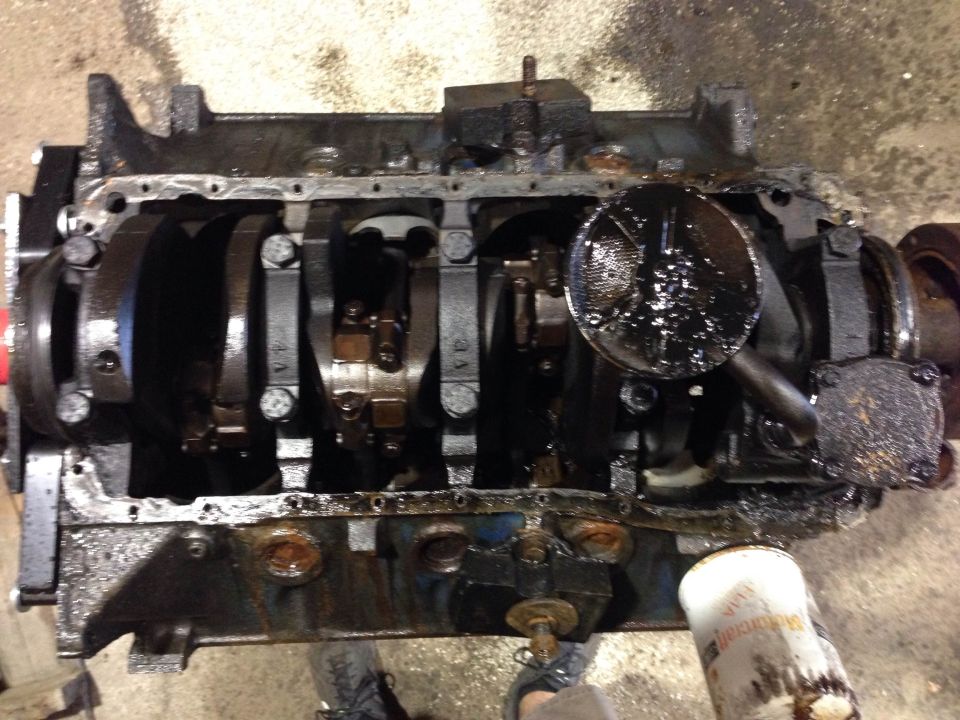 Dirty engine block with crankshaft, connecting rods, and oil filter.