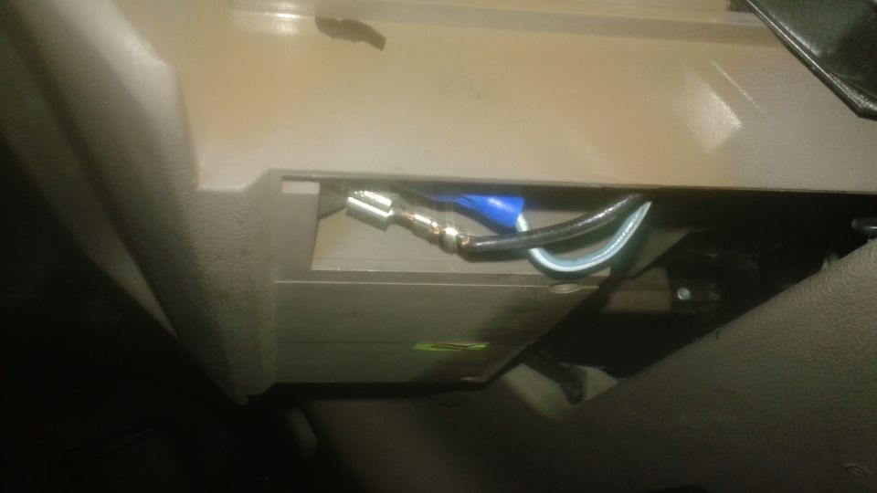 Close-up of electrical wiring with blue and silver connectors in a beige car interior.